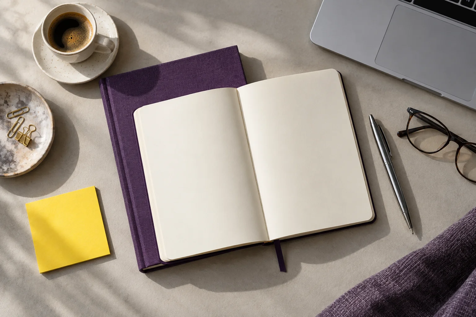 Editorial still life of a notebook, laptop and violet book
